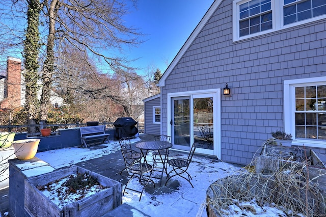 snow covered deck featuring area for grilling and a patio area