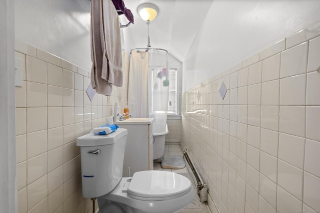 bathroom featuring vanity, toilet, tile walls, and lofted ceiling