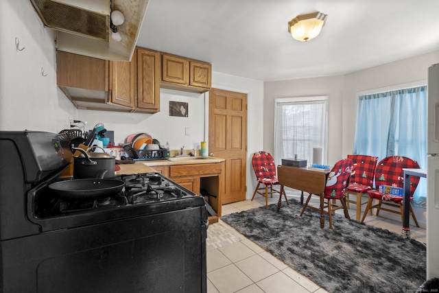 kitchen with black gas stove, light tile patterned floors, and sink