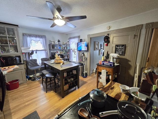 dining room featuring crown molding, light hardwood / wood-style flooring, ceiling fan, and a textured ceiling