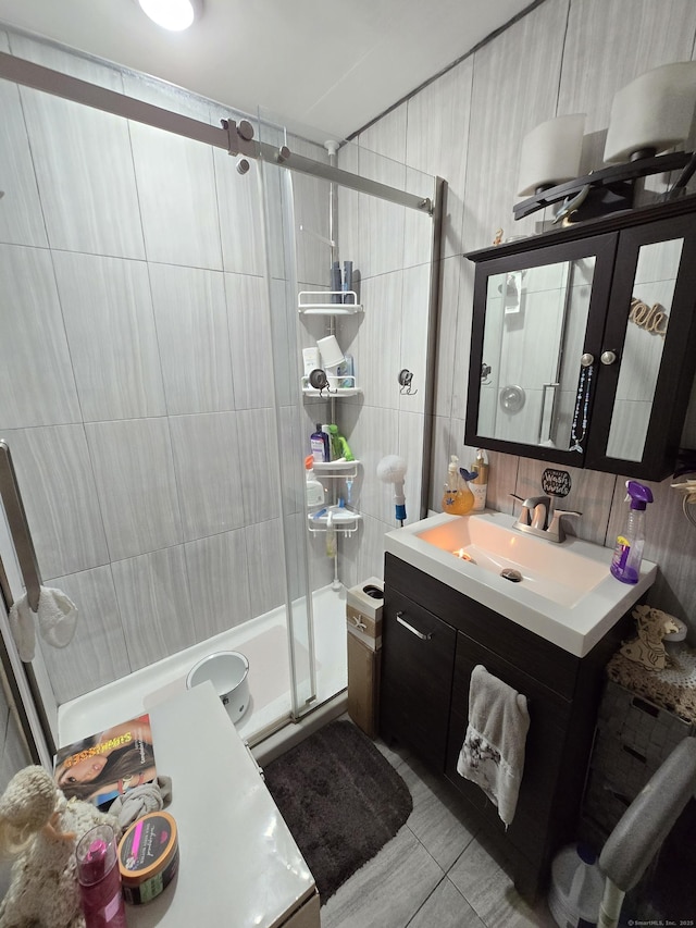 bathroom featuring tile patterned flooring, tile walls, vanity, and a shower with door