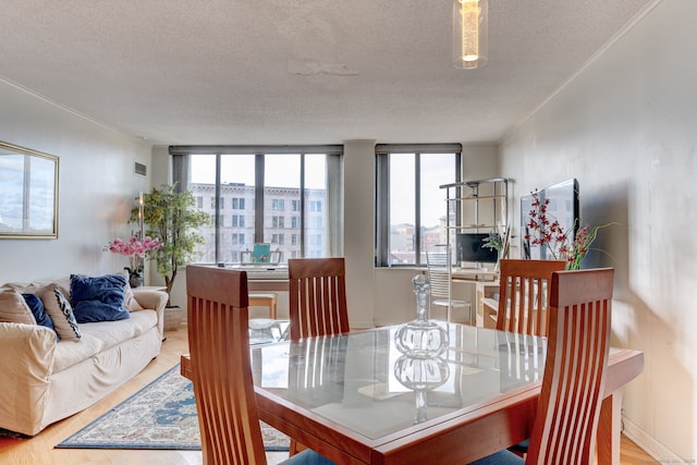 dining space featuring hardwood / wood-style floors, floor to ceiling windows, and a textured ceiling