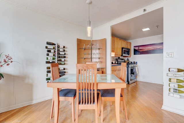 dining area with a textured ceiling and light hardwood / wood-style flooring