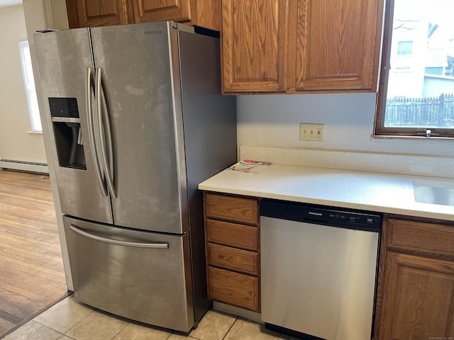 kitchen with light tile patterned flooring, a baseboard radiator, and appliances with stainless steel finishes