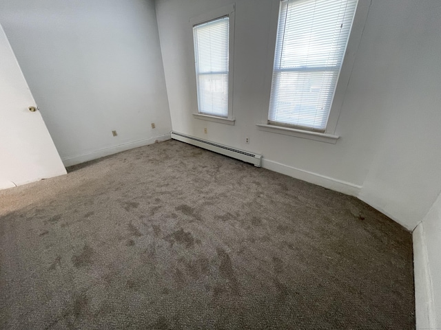 carpeted spare room featuring a baseboard heating unit