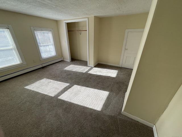 unfurnished bedroom featuring dark colored carpet, a textured ceiling, a closet, and a baseboard heating unit