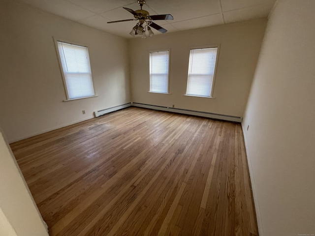 empty room with ceiling fan, light hardwood / wood-style floors, and baseboard heating