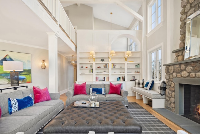 living room with wood-type flooring, a high ceiling, a fireplace, and ornamental molding