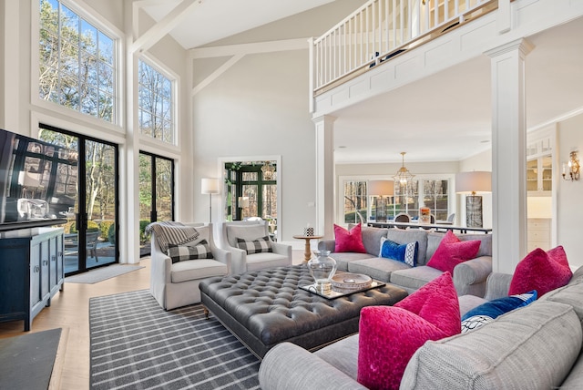 living room with a high ceiling, light wood-type flooring, decorative columns, and plenty of natural light