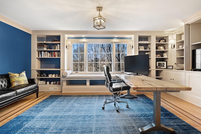 office space featuring wood-type flooring, a notable chandelier, crown molding, and built in features