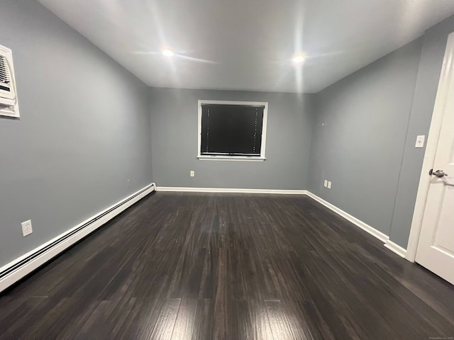 unfurnished room with dark hardwood / wood-style floors and a baseboard heating unit