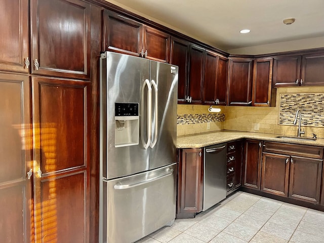 kitchen with sink, decorative backsplash, light stone countertops, appliances with stainless steel finishes, and light tile patterned flooring