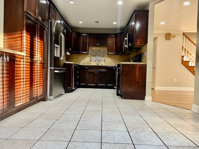 kitchen with light stone countertops, sink, stainless steel appliances, dark brown cabinets, and light tile patterned flooring