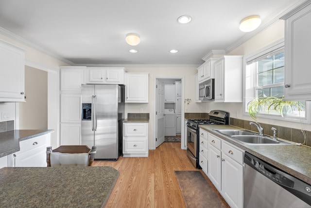 kitchen featuring sink, light hardwood / wood-style flooring, ornamental molding, appliances with stainless steel finishes, and white cabinetry