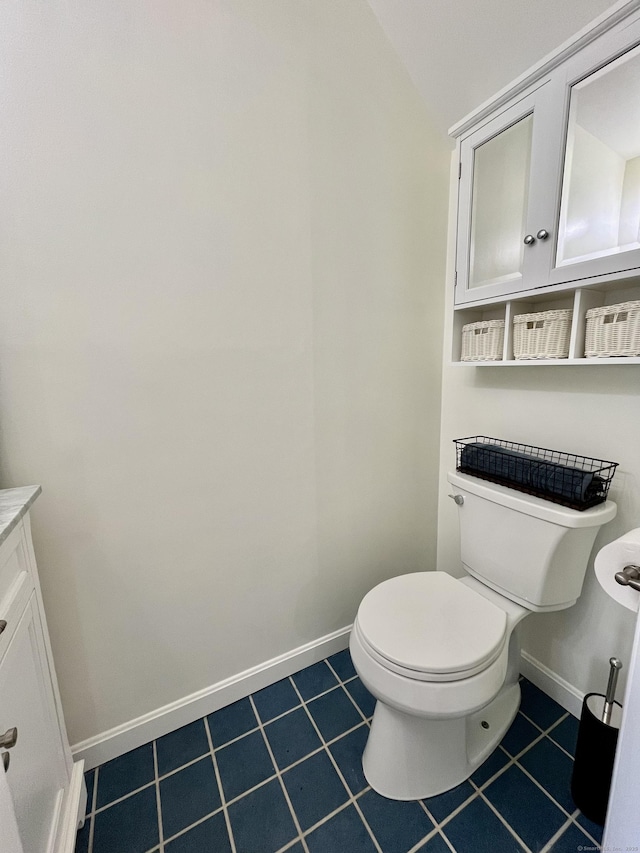 bathroom with tile patterned floors, vanity, toilet, and lofted ceiling