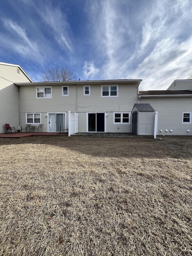 rear view of house with a storage shed and a deck