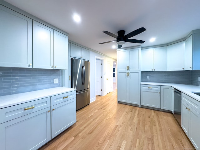 kitchen with light wood-type flooring, stainless steel appliances, ceiling fan, and backsplash