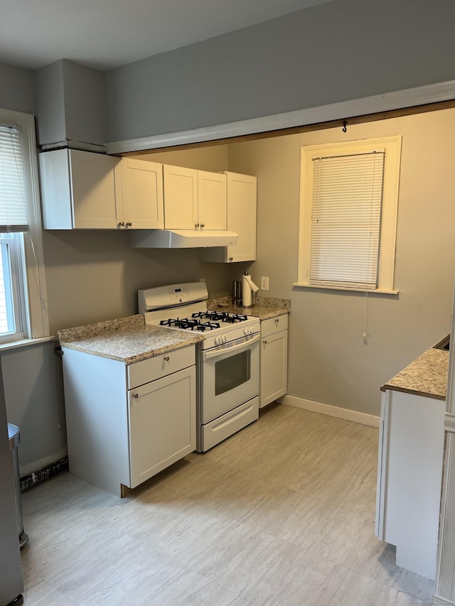 kitchen with white cabinets, light stone countertops, and gas range gas stove