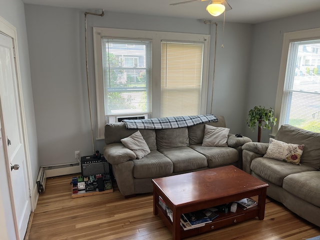 living room with light wood-type flooring, baseboard heating, and ceiling fan