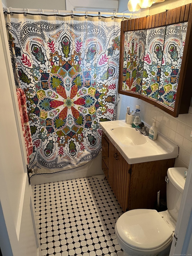 bathroom with vanity, backsplash, tile patterned flooring, toilet, and tile walls