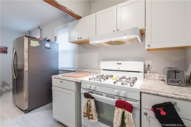 kitchen with white cabinets, white gas stove, and stainless steel refrigerator