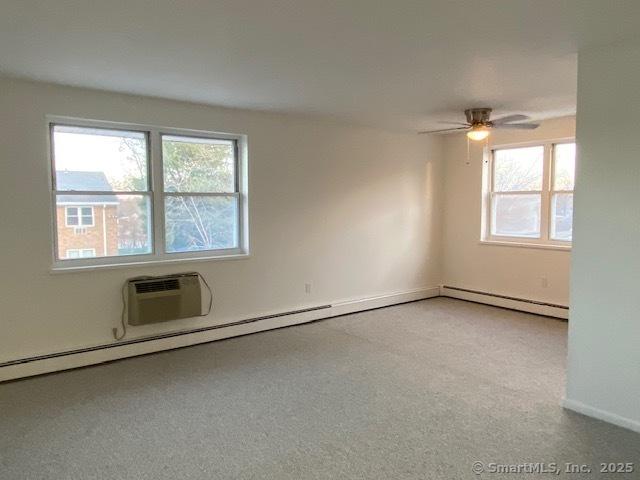 carpeted spare room with a wall mounted air conditioner and ceiling fan