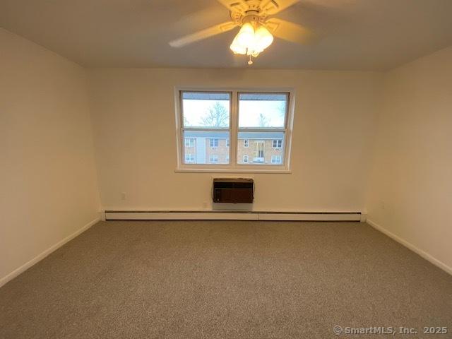 unfurnished room with carpet, a wall unit AC, and ceiling fan