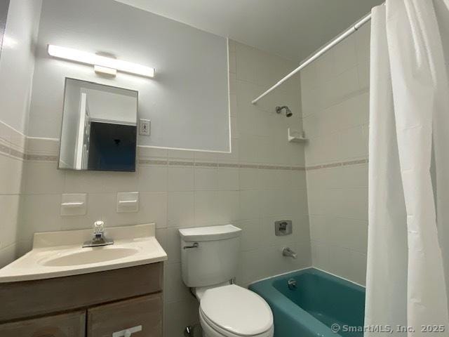 full bathroom with shower / bath combination with curtain, vanity, toilet, and tile walls