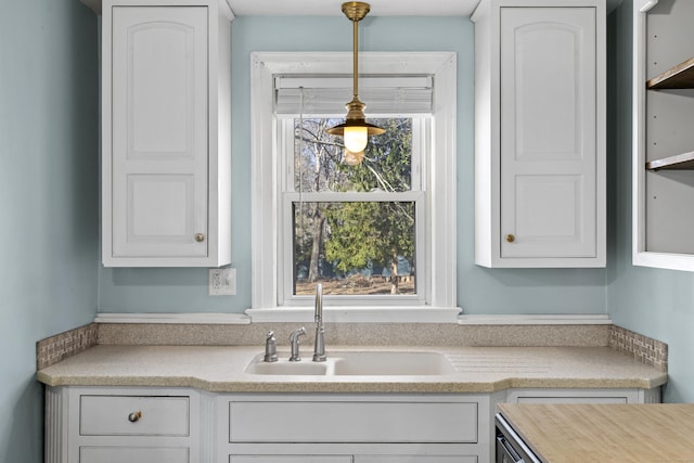 kitchen featuring decorative light fixtures, sink, and white cabinets