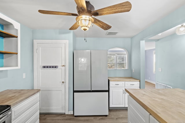 kitchen featuring white fridge, white cabinetry, light wood-type flooring, and wooden counters