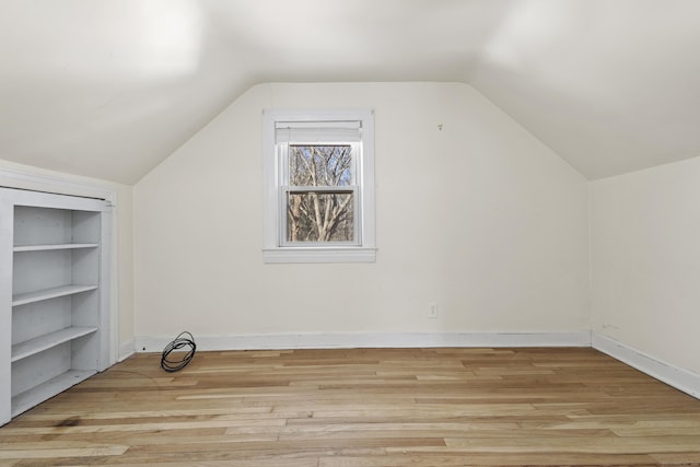 additional living space with vaulted ceiling and light hardwood / wood-style floors