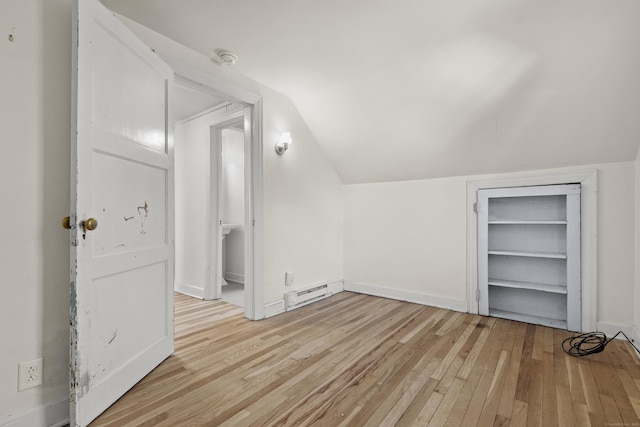 additional living space with a baseboard heating unit, lofted ceiling, and light wood-type flooring