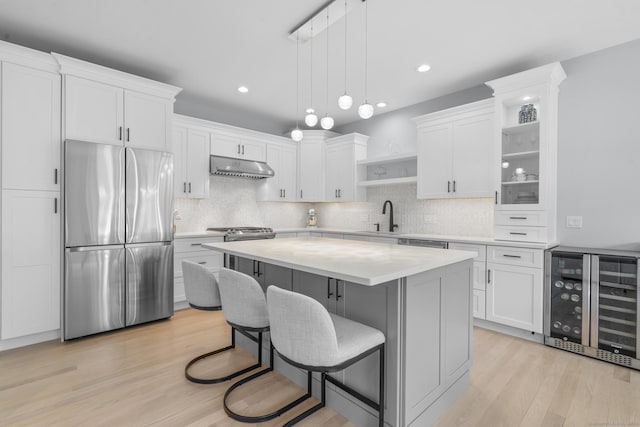 kitchen featuring white cabinetry, hanging light fixtures, wine cooler, light hardwood / wood-style flooring, and stainless steel fridge