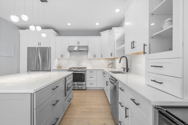 kitchen with white cabinetry, sink, stainless steel appliances, backsplash, and pendant lighting