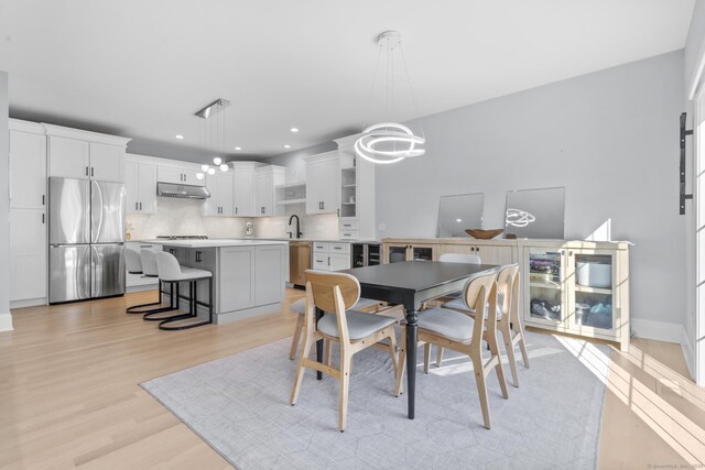 dining room with light hardwood / wood-style floors, sink, wine cooler, and an inviting chandelier