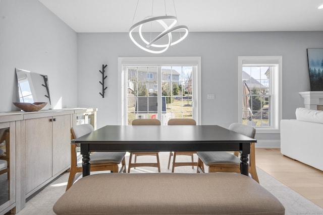 dining space featuring a healthy amount of sunlight, light wood-type flooring, and a notable chandelier