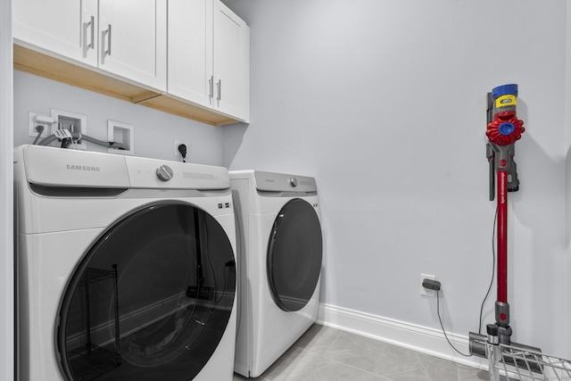 washroom featuring cabinets, light tile patterned floors, and washing machine and clothes dryer