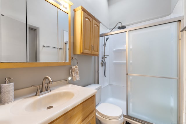 bathroom with toilet, a shower with shower door, and vanity