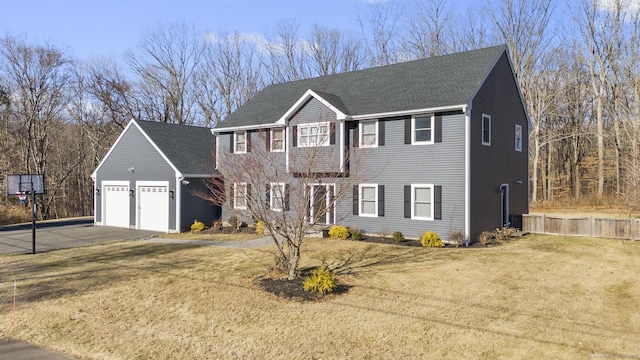 colonial-style house with a front yard, a garage, driveway, and a shingled roof