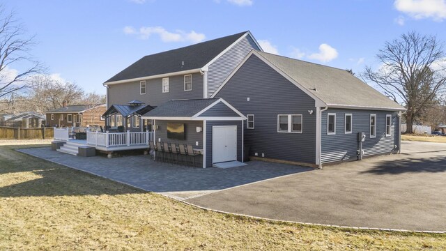 rear view of house with a wooden deck, a patio, a lawn, and outdoor dry bar