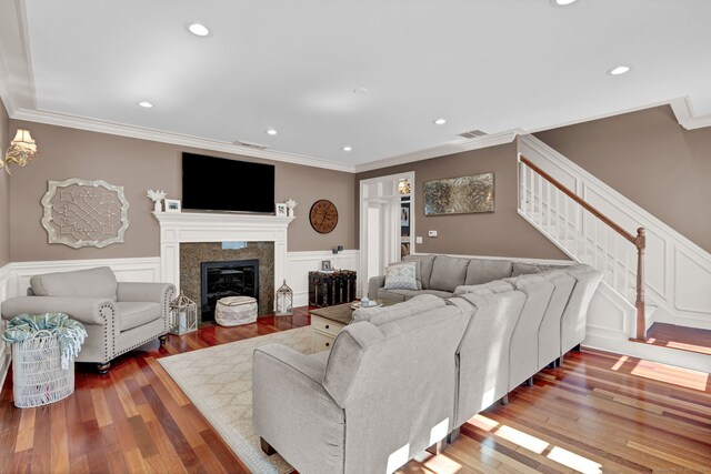 living area featuring visible vents, crown molding, stairway, a fireplace with flush hearth, and wood finished floors