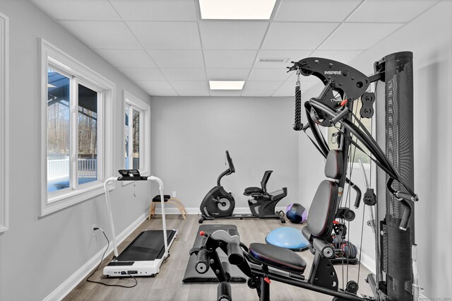 exercise area featuring a drop ceiling, baseboards, visible vents, and wood finished floors