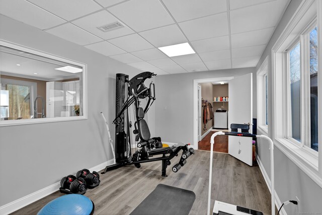 workout room featuring wood finished floors, visible vents, a drop ceiling, and baseboards