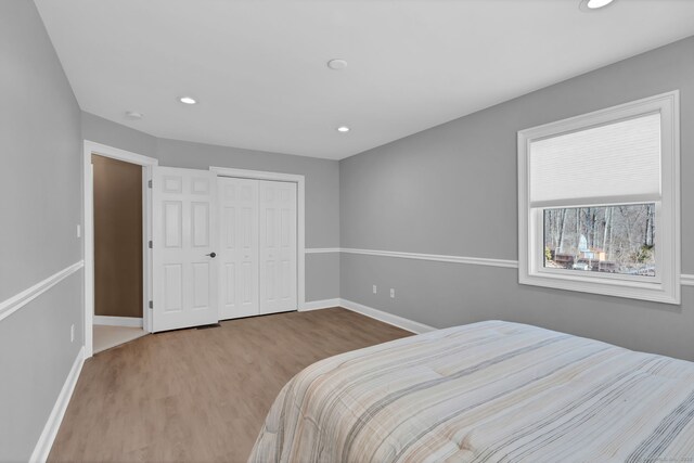 bedroom featuring recessed lighting, wood finished floors, baseboards, and a closet