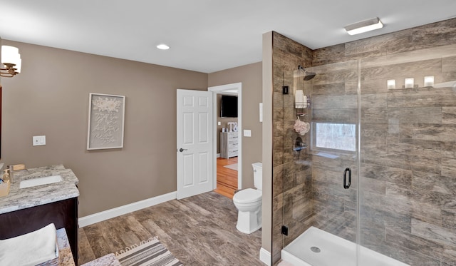 full bath with vanity, wood finished floors, baseboards, a shower stall, and toilet