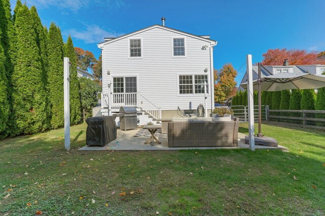 rear view of property with an outdoor living space, a patio area, and a lawn