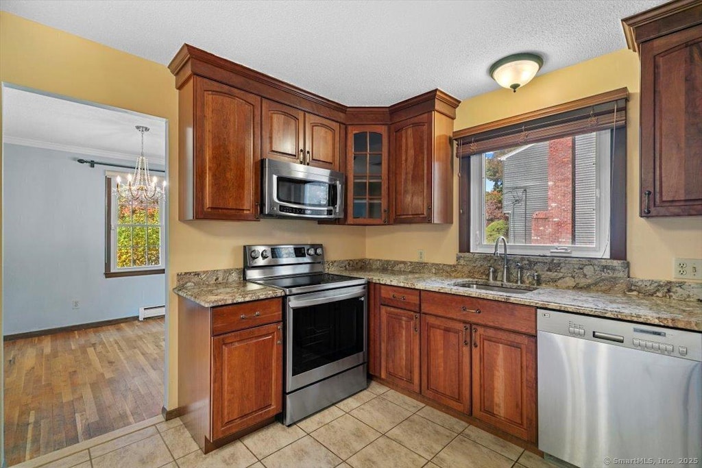 kitchen with light stone counters, sink, baseboard heating, and stainless steel appliances