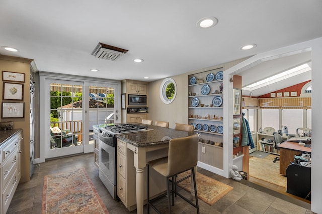 kitchen with dark stone countertops, vaulted ceiling, a breakfast bar, a kitchen island, and appliances with stainless steel finishes