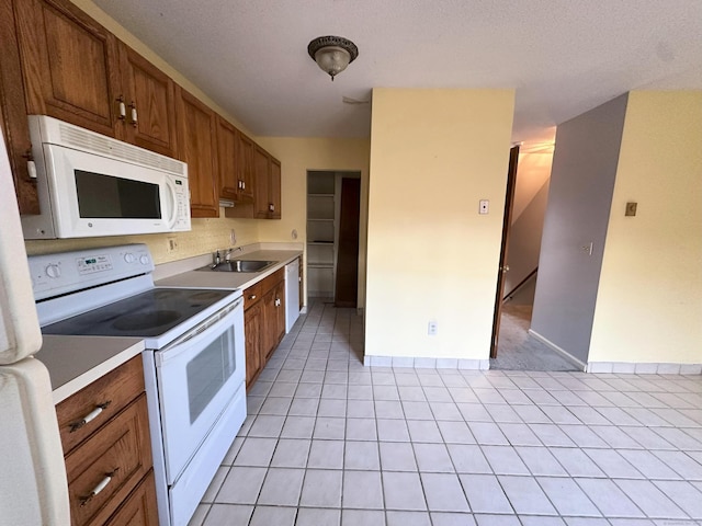 kitchen featuring sink, light tile patterned flooring, and white appliances