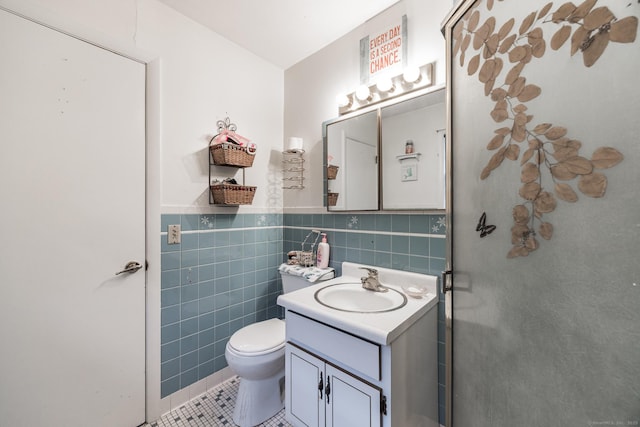 bathroom featuring toilet, vanity, tile patterned floors, and tile walls